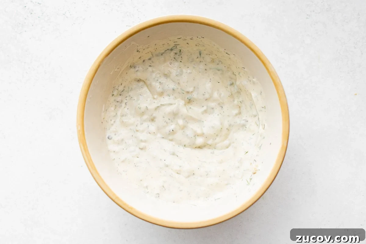 Creamy Homemade Tartar Sauce Recipe for Fish and Seafood 6 Fully mixed tartar sauce in a beige bowl, showing creamy texture with flecks of herbs and pickles.