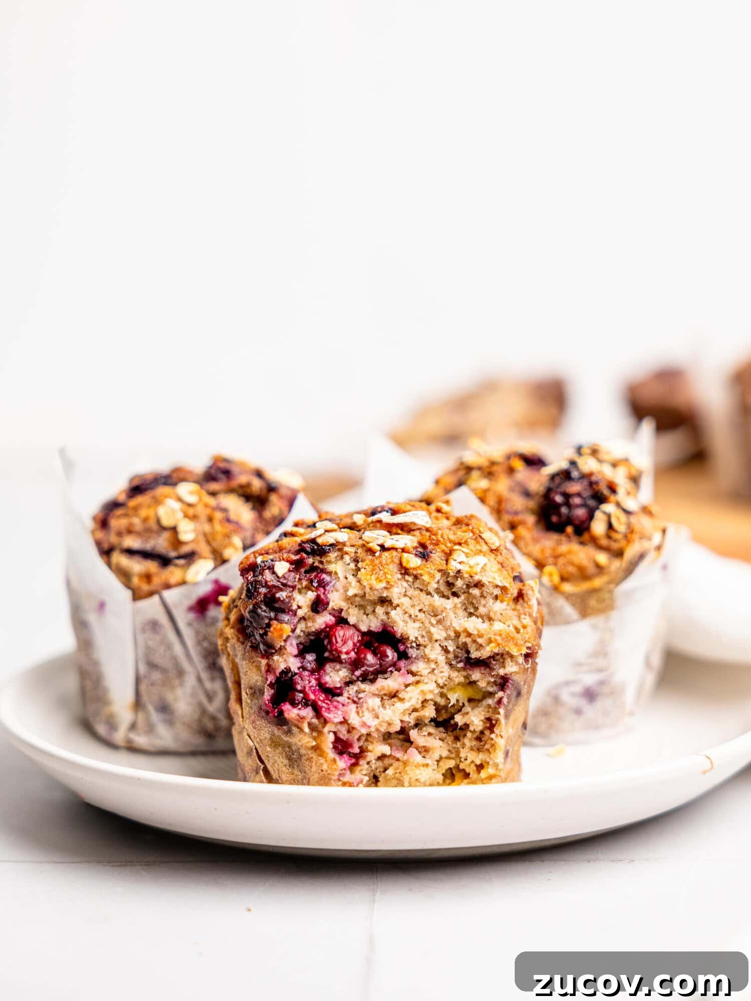 Banana Blackberry Muffins with 5 Simple Ingredients 2 Three blackberry oatmeal muffins on a white plate.