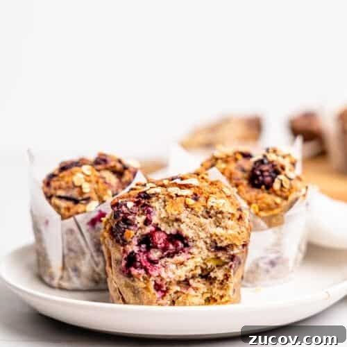 Banana Blackberry Muffins with 5 Simple Ingredients 12 Three blackberry oatmeal muffins on a white plate.