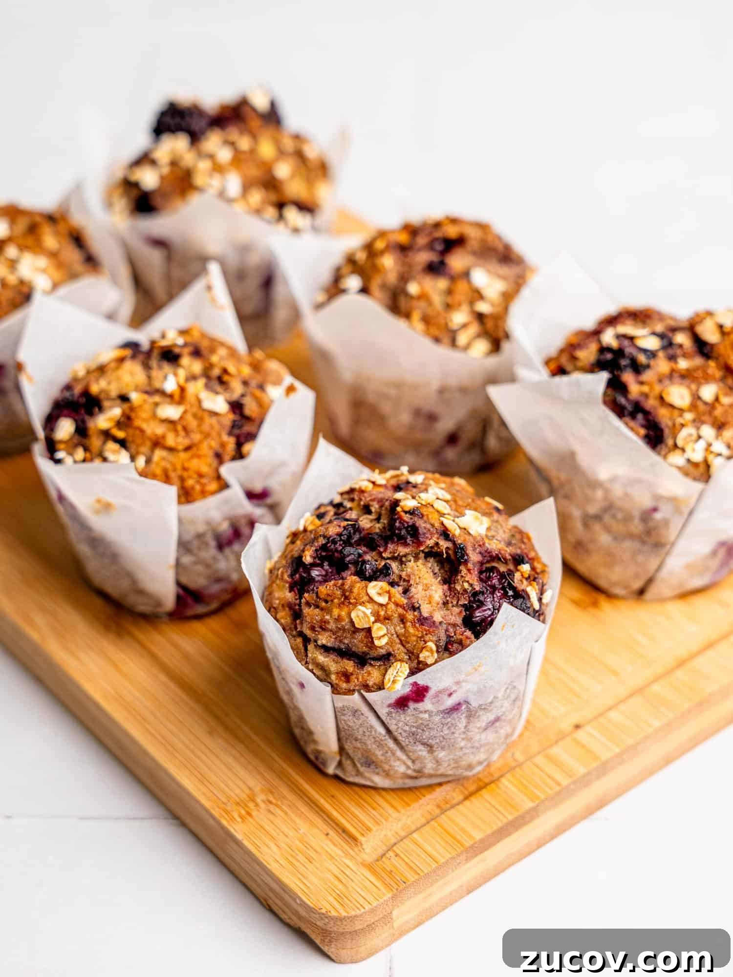 Banana Blackberry Muffins with 5 Simple Ingredients 4 Six Banana Blackberry Muffins on a wooden board.