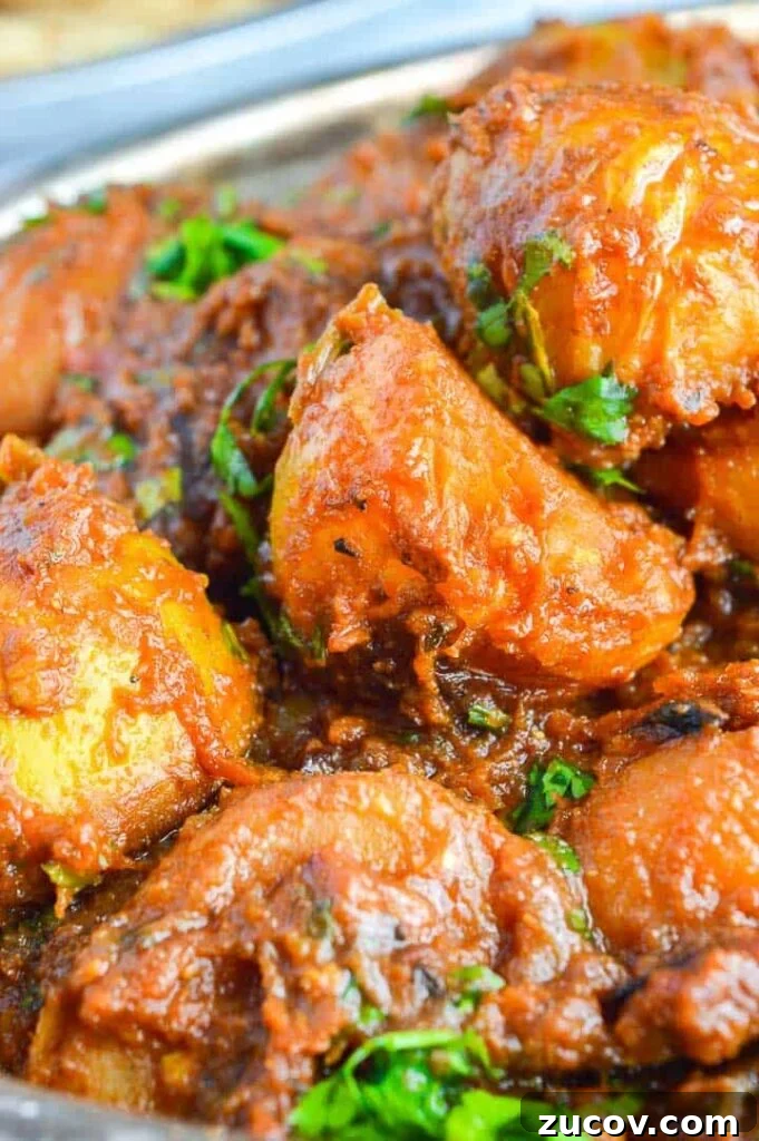 Bombay Potatoes Recipe: Restaurant-Style Spiced Potatoes 4 Close up of halved potatoes in a brown curry sauce with fresh cilantro sprinkled on top
