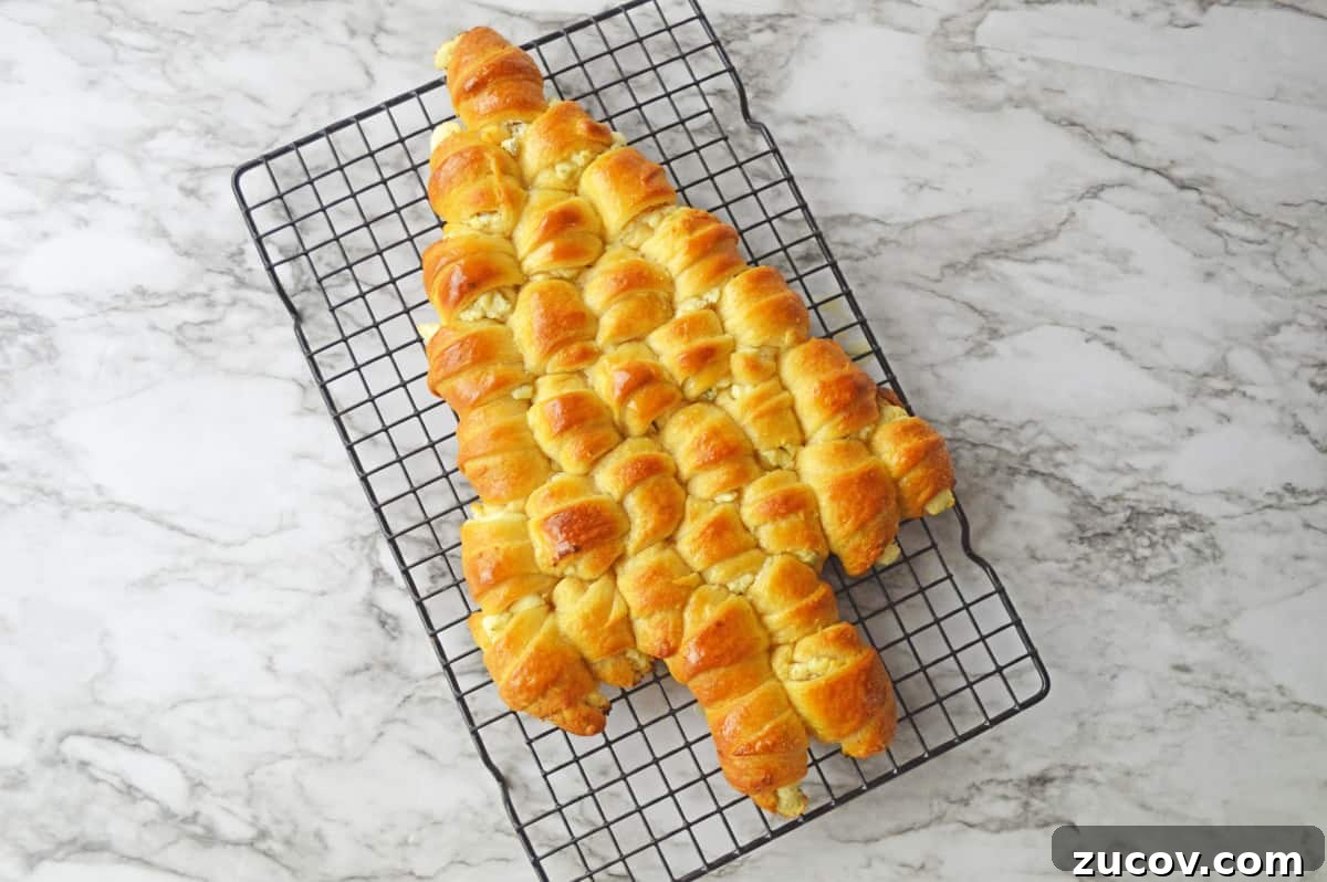 Golden brown crescent roll Christmas tree on wire cooling rack.