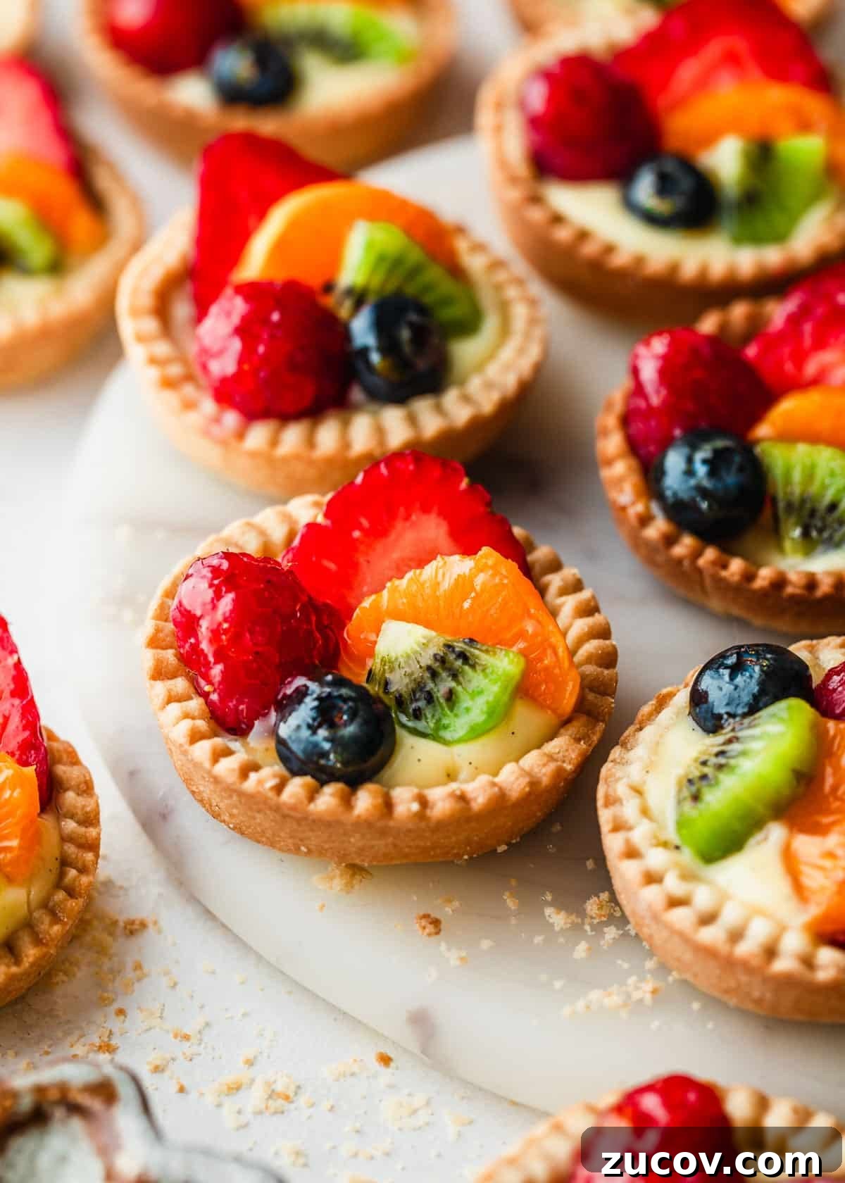 Fresh Fruit Tartlets with Silky Pastry Cream Recipe 17 A white tray of mini fruit tartlets on a white counter.