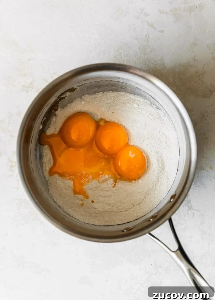 Fresh Fruit Tartlets with Silky Pastry Cream Recipe 6 A silver pot of sugar, cornstarch, and egg yolks on a white counter.