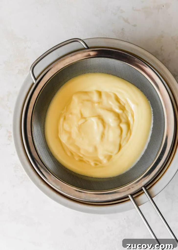 Fresh Fruit Tartlets with Silky Pastry Cream Recipe 10 Pastry cream being strained through a fine mesh sieve.