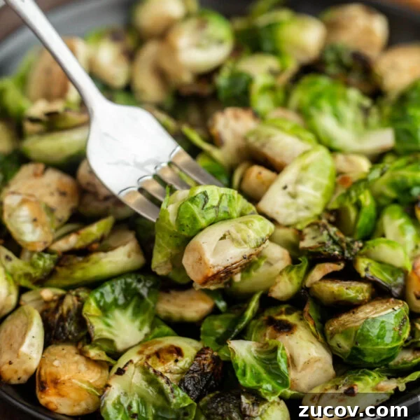 February Blackstone Chicken Recipes: What to Grill This Month 15 A close-up of Blackstone Brussels sprouts on a plate, with a fork spearing one piece.