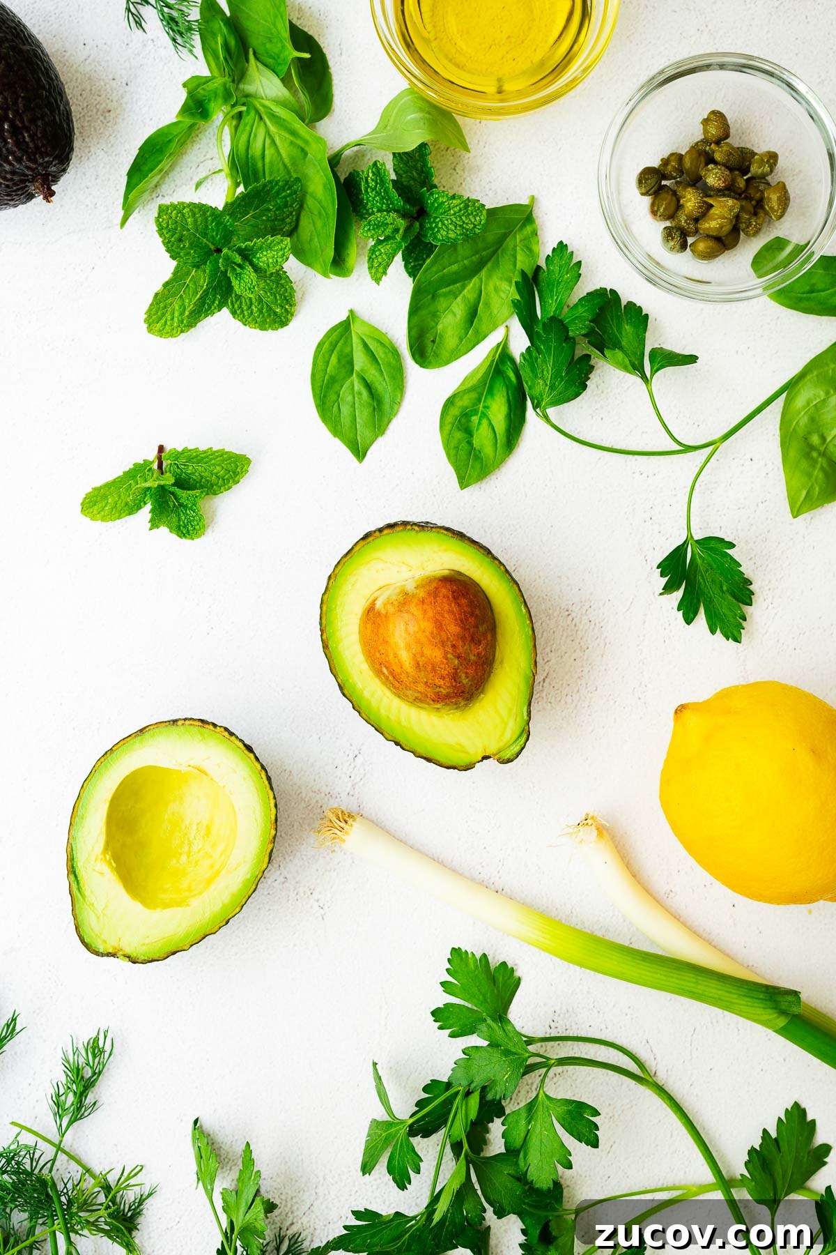 Creamy Avocado Green Goddess Dressing Recipe for Salads and Bowls 3 Ingredients for an avocado green goddess dressing on a light concrete surface.