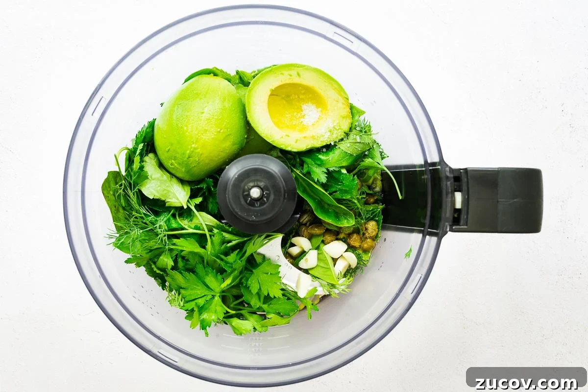 Creamy Avocado Green Goddess Dressing Recipe for Salads and Bowls 5 Ingredients for an avocado green goddess sauce in the bowl of a food processor viewed from above.