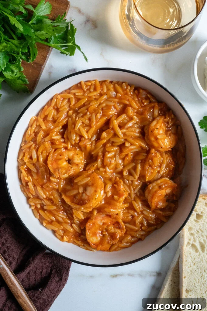 Garides Youvetsi: Greek Shrimp with Orzo Recipe 11 Garides youvetsi, Greek shrimp with orzo. In a white bowl surrounded by feta, bread, a fork, a napkin and wine.