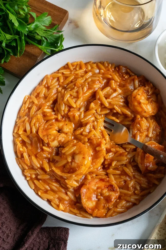 Garides Youvetsi: Greek Shrimp with Orzo Recipe 12 Garides youvetsi, Greek shrimp with orzo. In a white bowl surrounded by feta, bread, a fork, a napkin and wine.