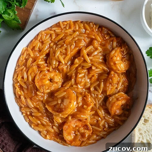 Garides Youvetsi: Greek Shrimp with Orzo Recipe 16 Garides youvetsi, Greek shrimp with orzo. In a white bowl surrounded by feta, bread, a fork, a napkin and wine.