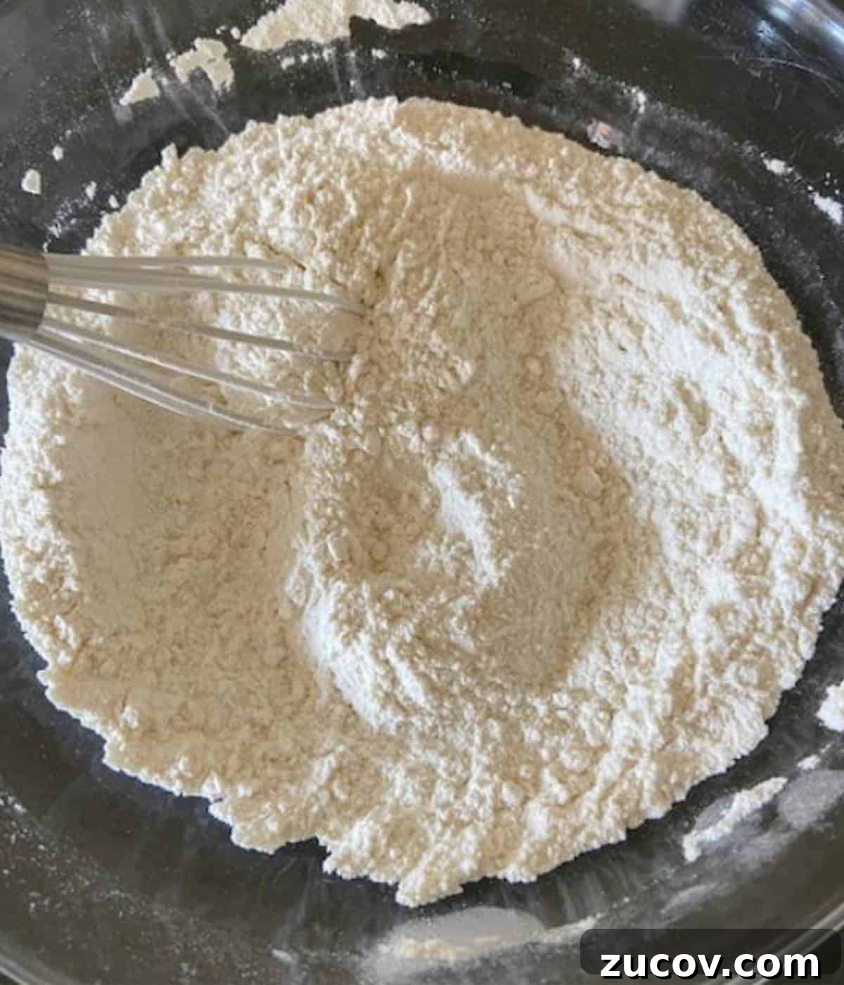 Chewy White Chocolate Chip Cookie Recipe for Perfect Bakes 4 Dry ingredients for white chocolate cookies in glass bowl with whisk.