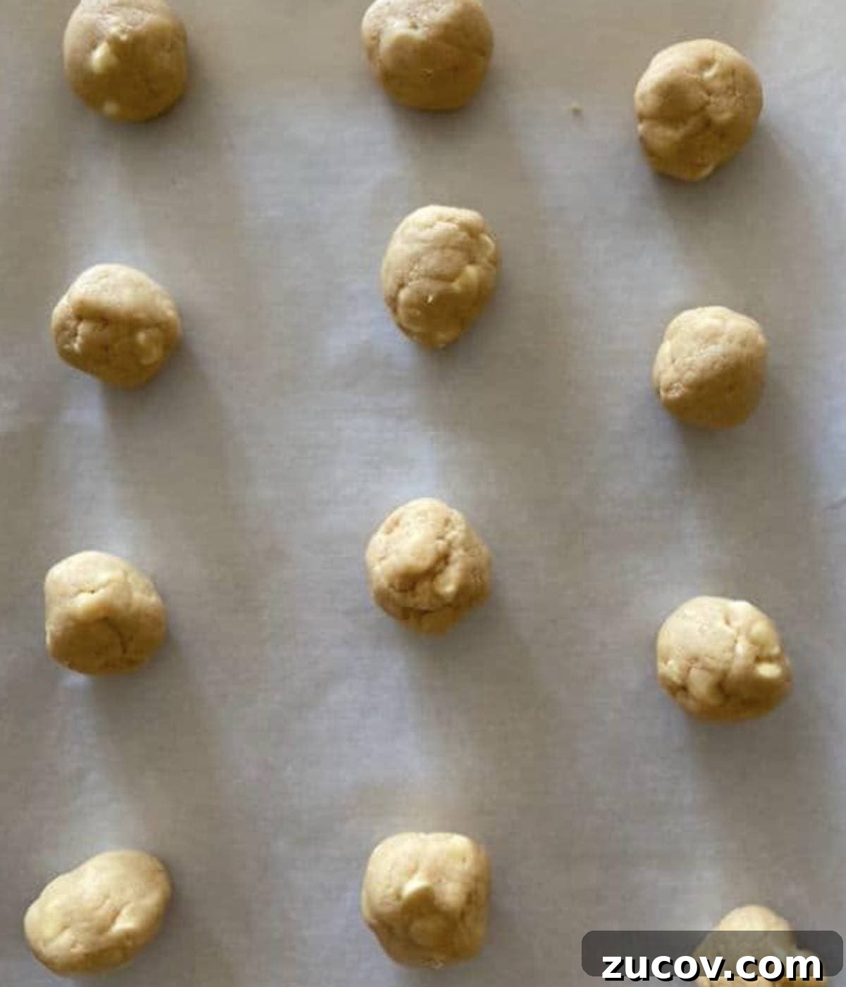 Chewy White Chocolate Chip Cookie Recipe for Perfect Bakes 7 Cookies rolled into balls on parchment lined cookie sheet.