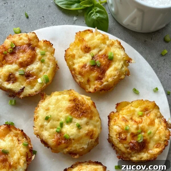 No-Knead Focaccia Recipe: Crispy, Olive Oil-Rich Bread in One Pan 19 Six golden-brown baked egg muffins topped with chopped green herbs are arranged on a white round serving board, next to a sprig of basil and a bowl of cheesy smashed potatoes on a gray surface.