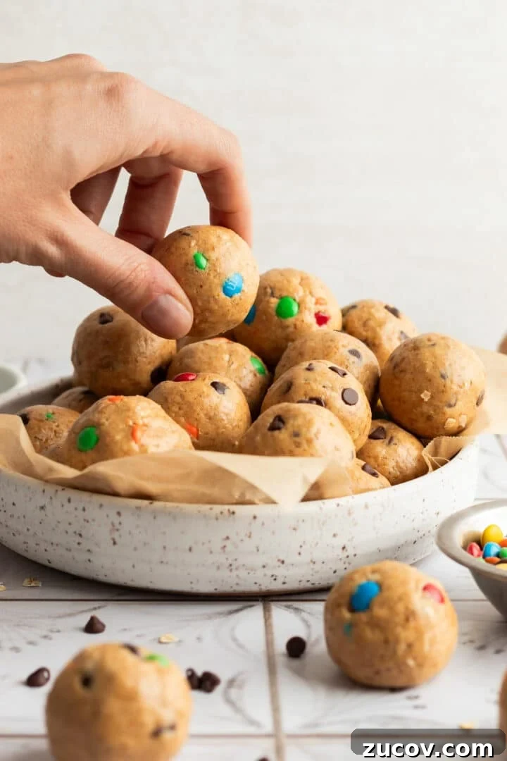Cookie Dough Protein Balls: No-Bake Snack for Energy and Muscle 9 Cookie dough protein balls in a large white bowl, with a woman's hand grabbing one to eat