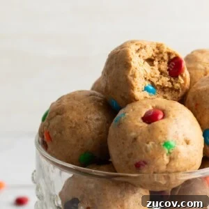 Cookie Dough Protein Balls: No-Bake Snack for Energy and Muscle 10 Close-up photo of cookie dough protein balls with mini m&m candies and mini chocolate chips, with a bite taken out of one