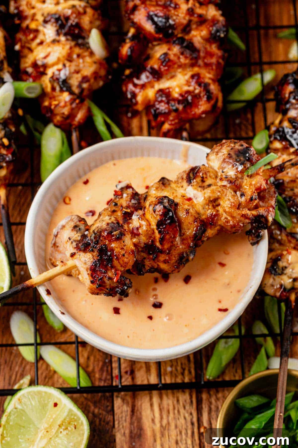 Bang Bang Chicken Skewers Recipe: Creamy Spicy Grilled Skewers 3 dipping a grilled bang bang chicken skewer into a bowl of bang bang sauce.