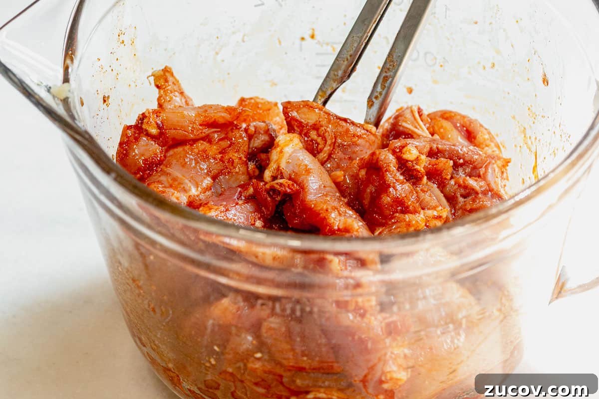 Bang Bang Chicken Skewers Recipe: Creamy Spicy Grilled Skewers 4 tossing cubed chicken thighs with olive oil and spices in a bowl.