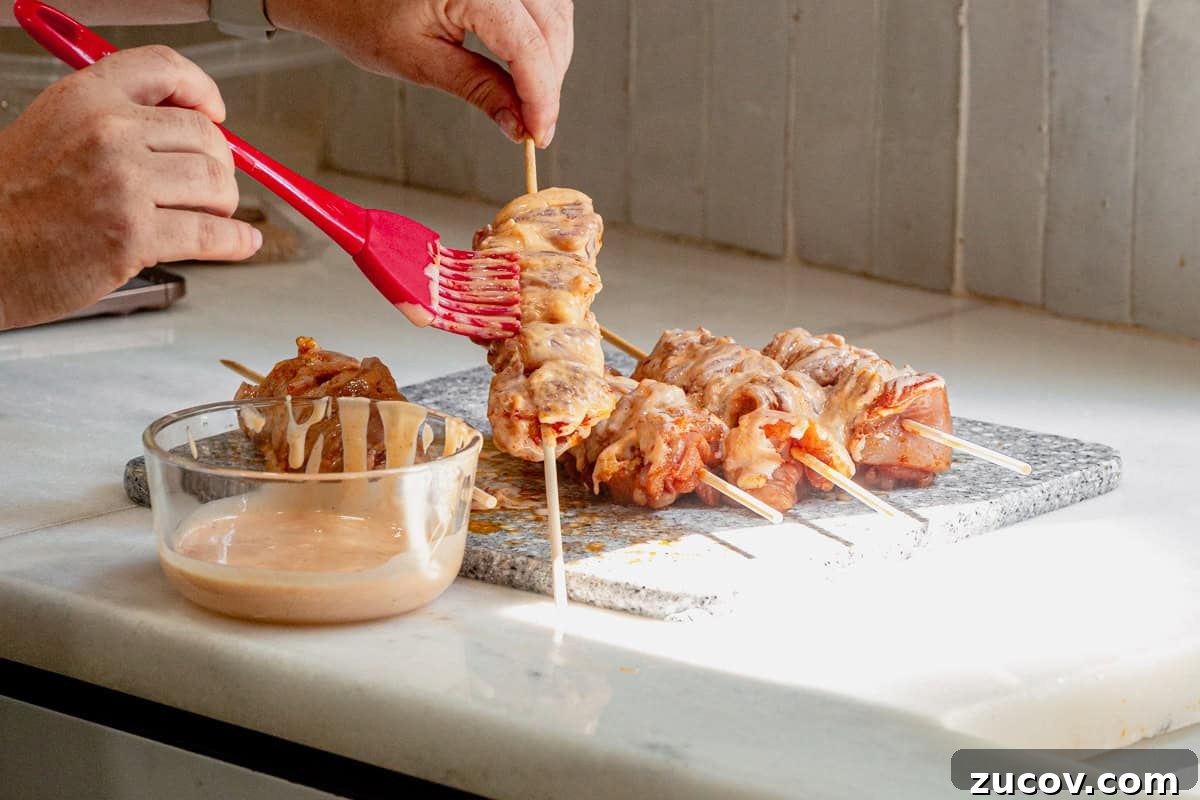 Bang Bang Chicken Skewers Recipe: Creamy Spicy Grilled Skewers 6 Brushing bang bang sauce onto chicken skewers.