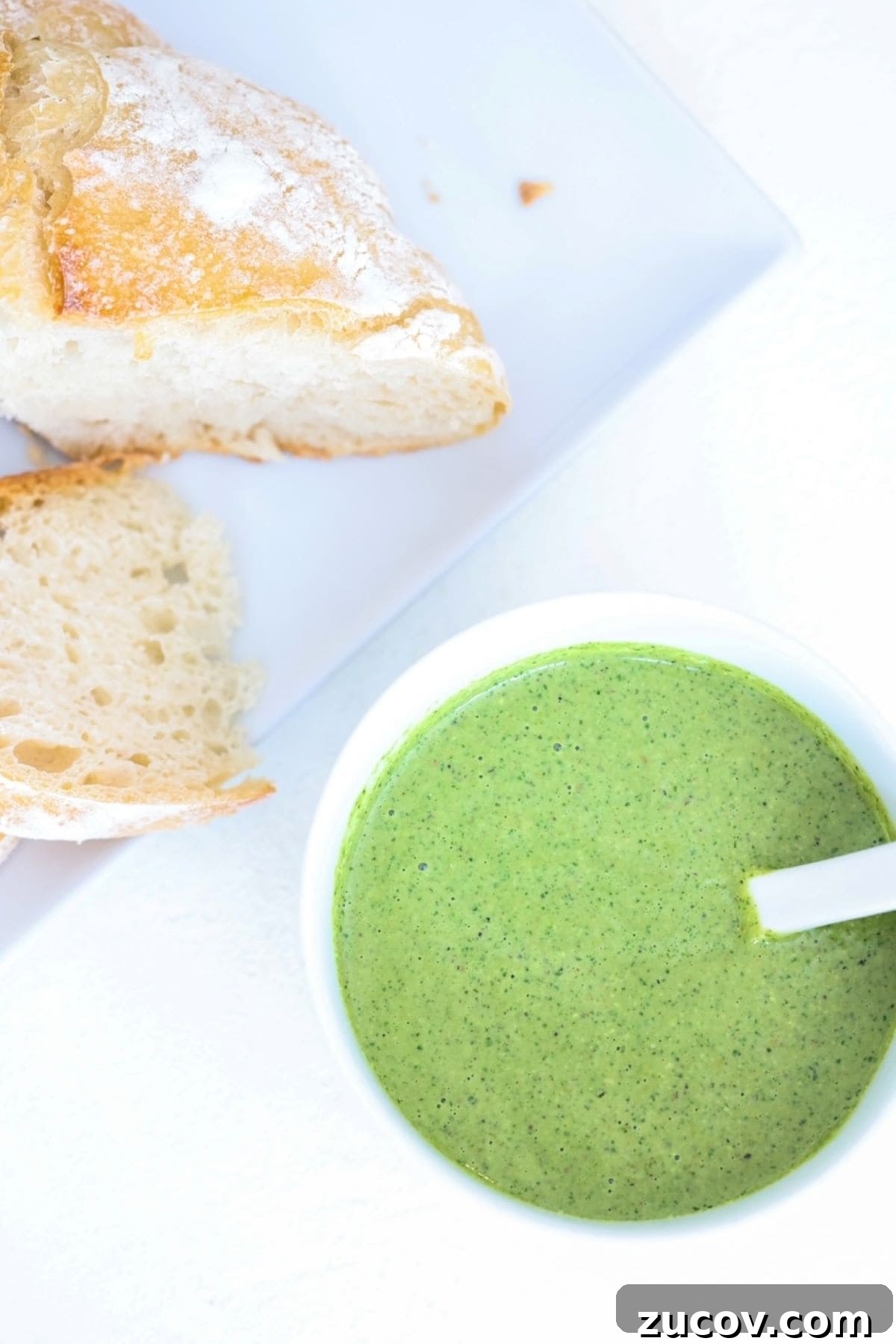 Quick Pistachio Pesto Recipe Ready in 5 Minutes 2 Pesto in a white bowl and two slices of sourdough bread on a white plate.