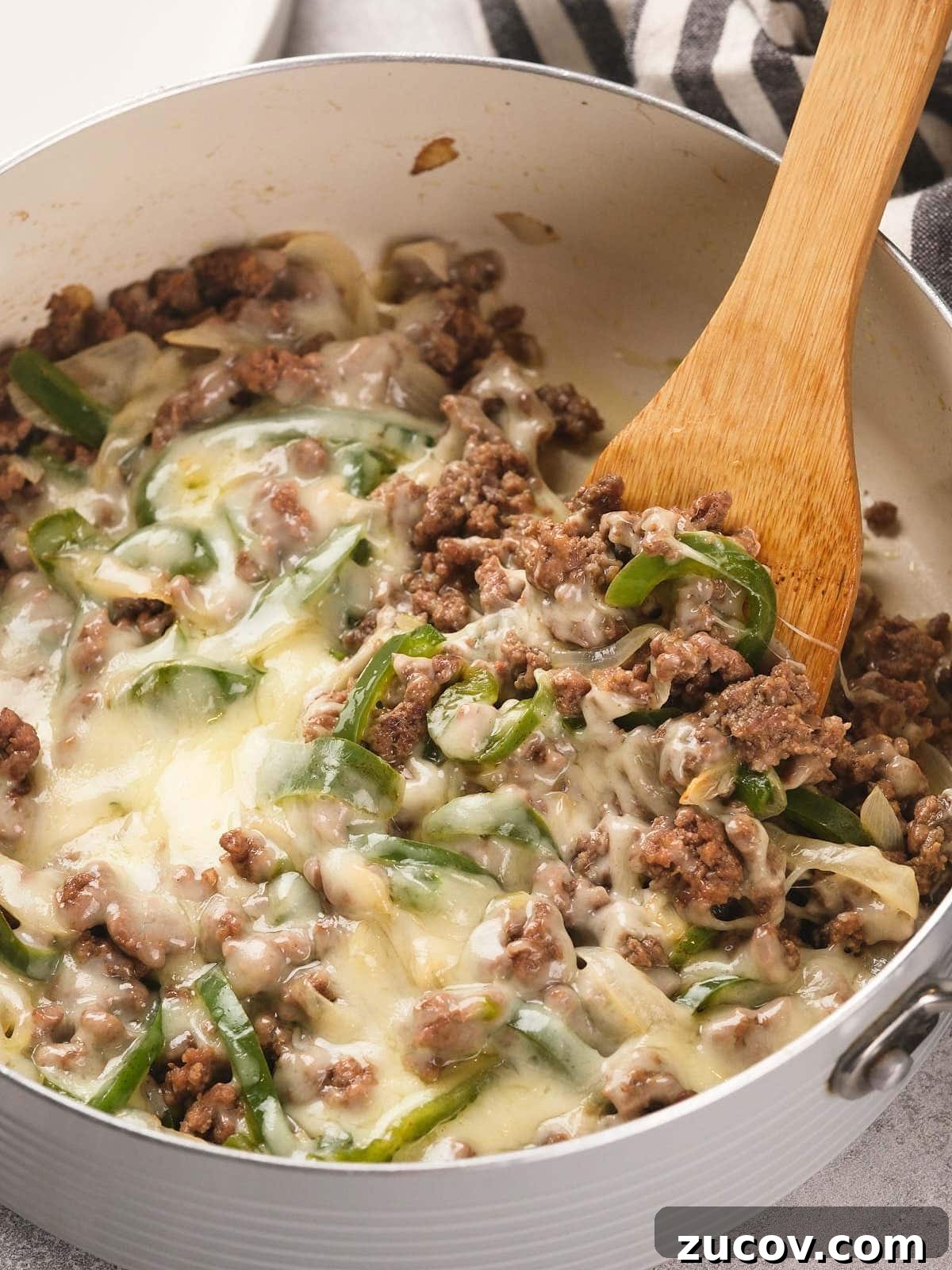28 Low-Histamine Recipes for Histamine Intolerance-Friendly Meals 9 Ground beef, melted cheese, sliced green bell peppers, and onions are mixed together in a white pan with a wooden spoon.