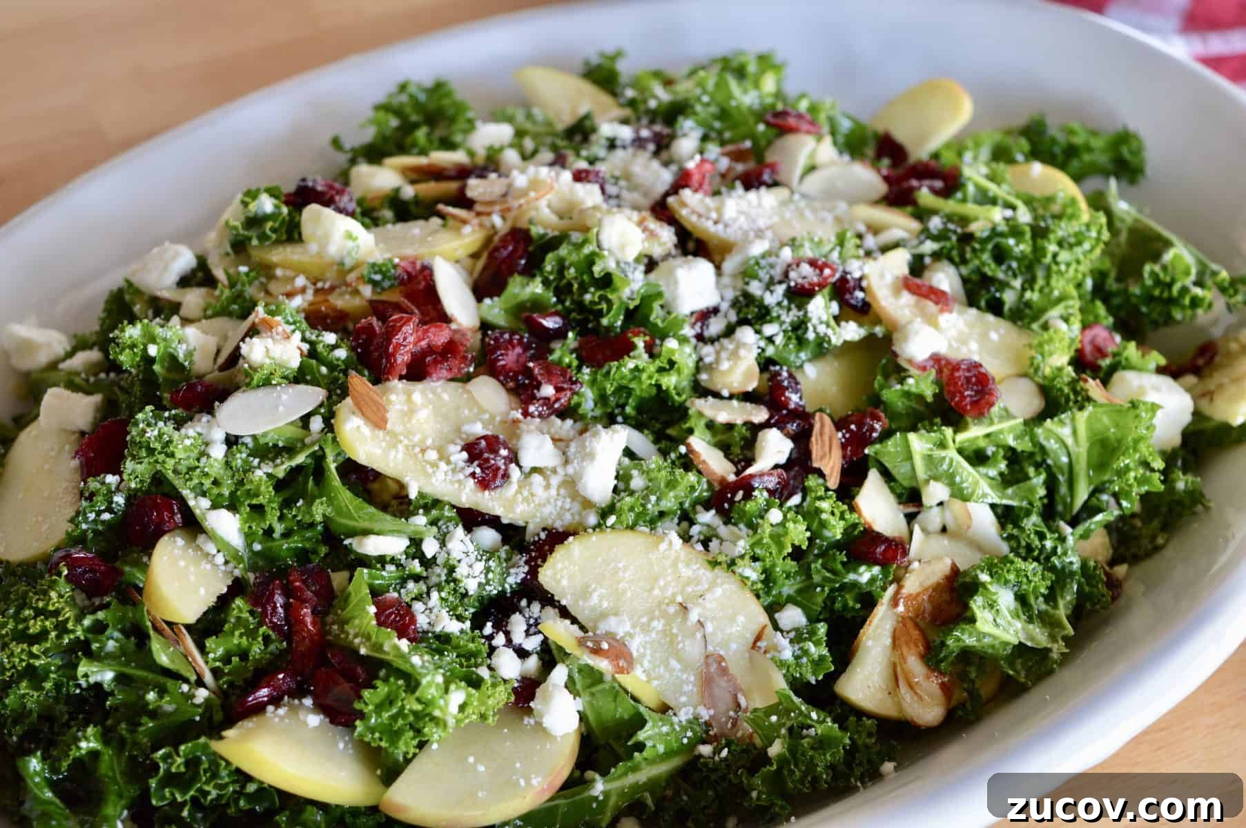 Kale, Cranberry & Feta Salad with Lemon Vinaigrette 2 Kale Cranberry Feta Salad with almonds and apples in a white serving platter.