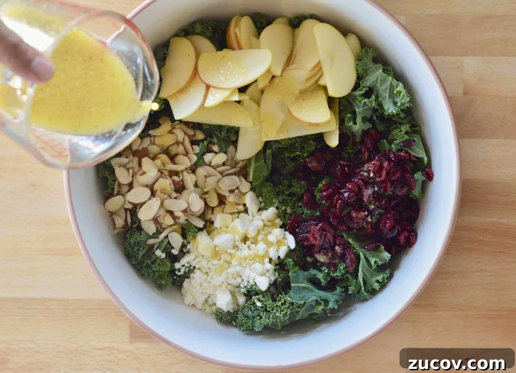 Kale, Cranberry & Feta Salad with Lemon Vinaigrette 5 lemon vinaigrette poured over ingredients in large bowl.