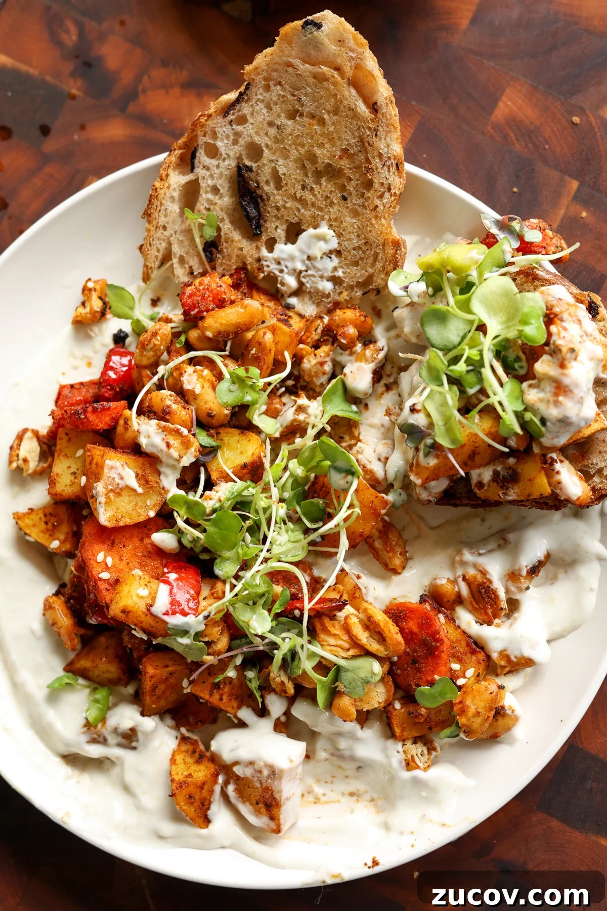 Roasted Veggies and White Beans with Lemon Yogurt Sauce 3 sheet pan veggies and beans over creamy lemon yogurt sauce on a white plate with bread for dipping