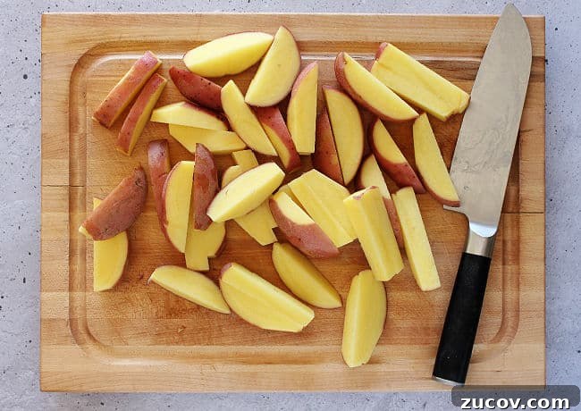 Crispy Roasted Parmesan Potato Wedges with Garlic and Herbs 4 Raw potato wedges on a cutting board.