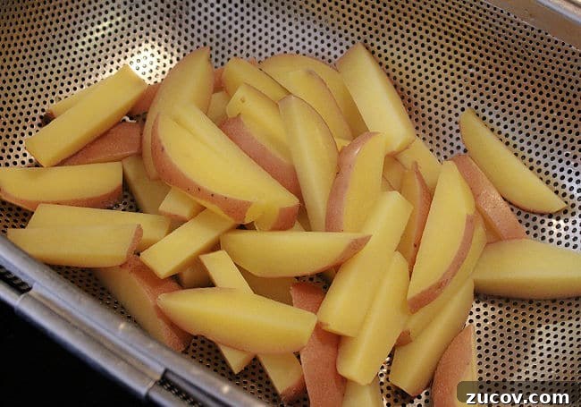 Crispy Roasted Parmesan Potato Wedges with Garlic and Herbs 6 Draining parbaked potato fries in a sieve.