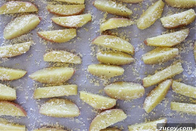 Crispy Roasted Parmesan Potato Wedges with Garlic and Herbs 8 Unbaked parmesan-covered potatoes on a baking sheet.