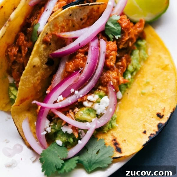 Crispy Baja Fish Tacos with Tangy Slaw and Lime Crema 3 Chicken tinga tacos fully assembled and ready to be enjoyed, topped with red onions, cilantro, cheese, and more.