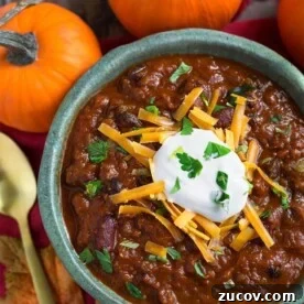 Instant Pot Pumpkin Chili Recipe for Cozy Weeknight Dinners 6 Pumpkin Chili topped with shredded cheese and sour cream in a turquoise bowl