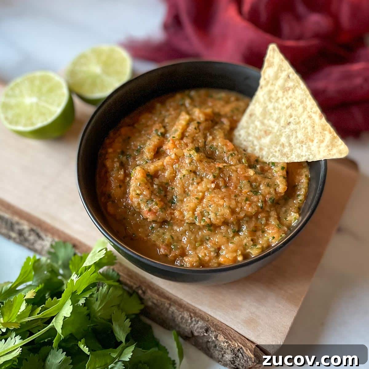 Freeze Habanero Peppers: Simple Steps to Preserve Heat and Flavor 9 A bowl of pineapple habanero salsa sits on a rustic wooden cutting board surrounded by limes, cilantro, and a red linen.