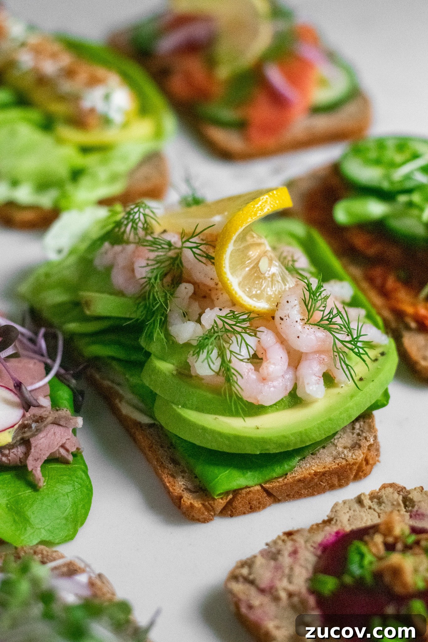 How a Sandwich Became Denmark’s Iconic Smørrebrød: Complete Guide 13 A rye bread open faced sandwich topped with lettuce, avocado, baby shrimp, dill, and lemon.