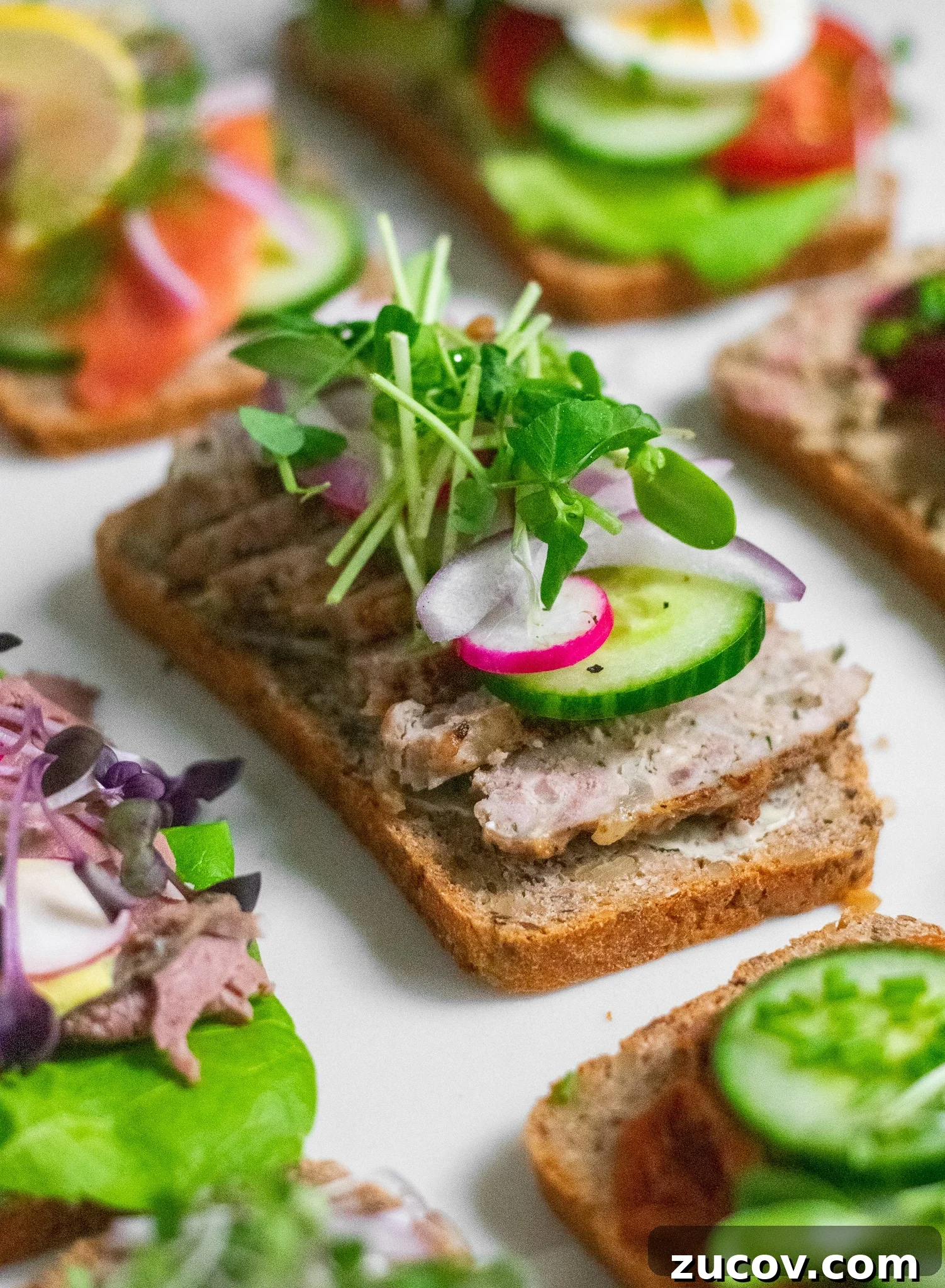 How a Sandwich Became Denmark’s Iconic Smørrebrød: Complete Guide 14 A rye bread open faced sandwich topped with danish meatballs, cucumber, radish, onion, and micro greens.