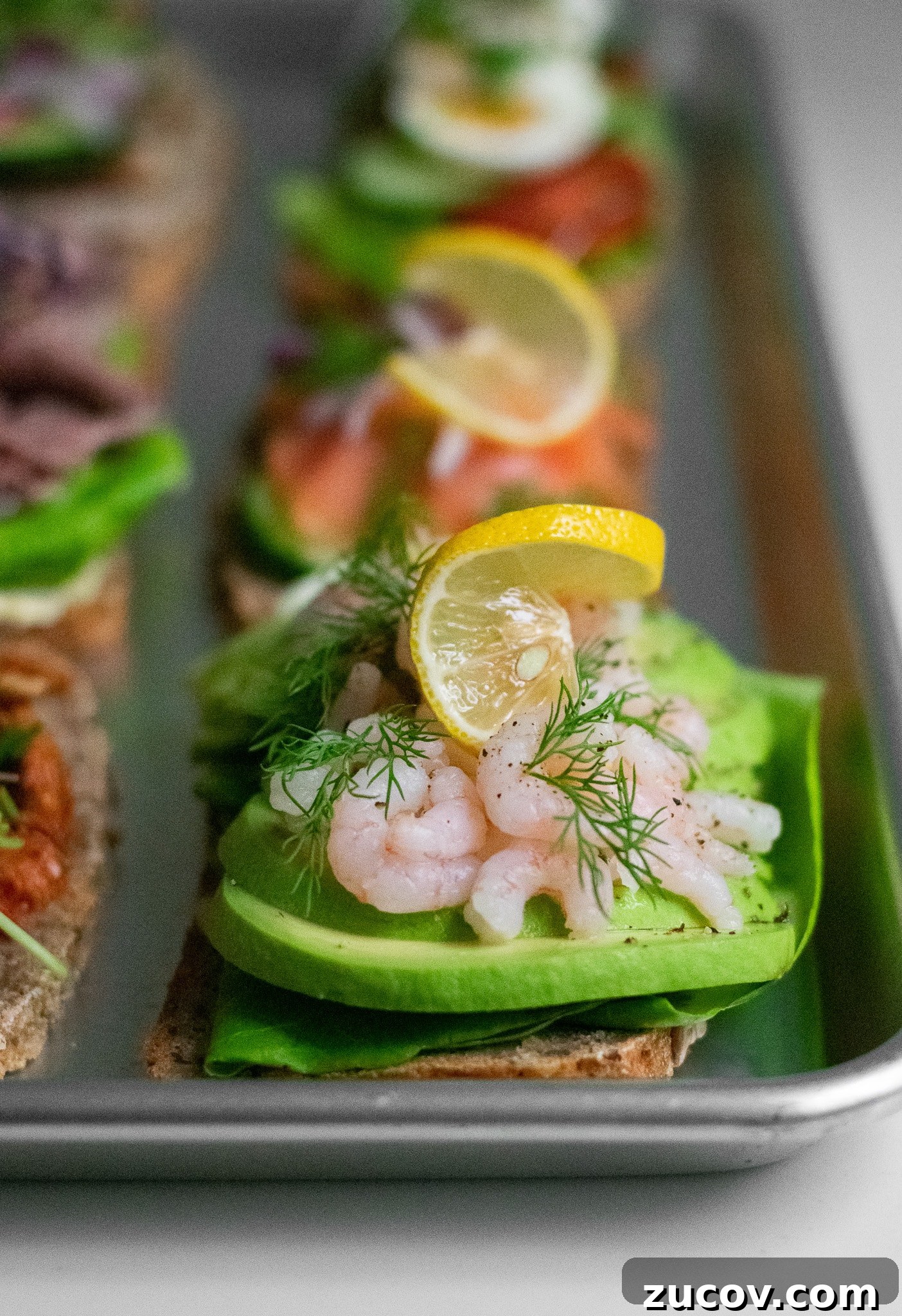 How a Sandwich Became Denmark’s Iconic Smørrebrød: Complete Guide 4 A rye bread open faced sandwich topped with lettuce, avocado, baby shrimp, dill, and lemon.