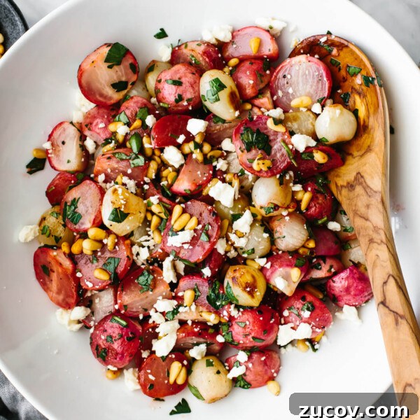 Roasted radish salad in a large white bowl next to cheese