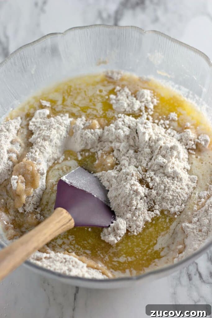 Coconut Butter Bars Recipe with Creamy Coconut Filling 5 Dry ingredients being added to wet ingredients in a mixing bowl.