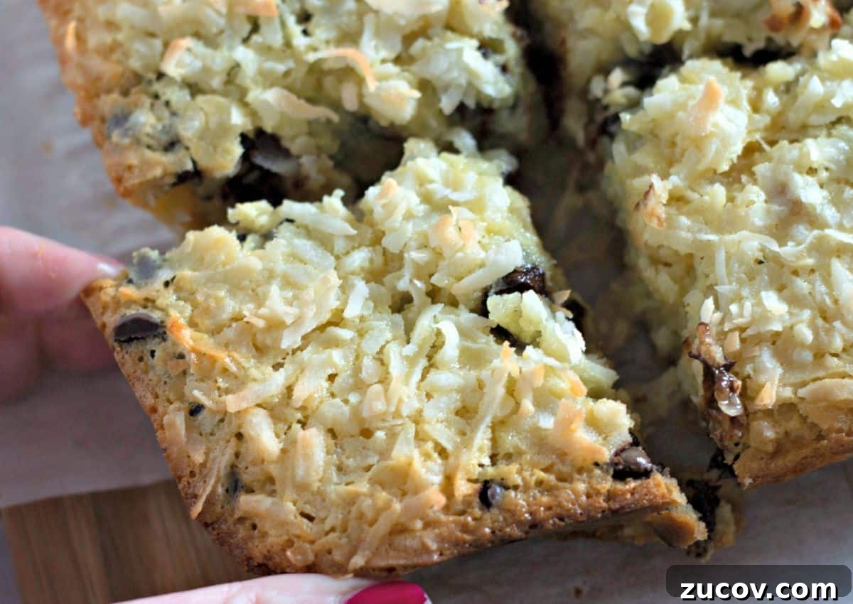 Coconut Butter Bars Recipe with Creamy Coconut Filling 10 Coconut butter bar being grabbed by a woman's hand.