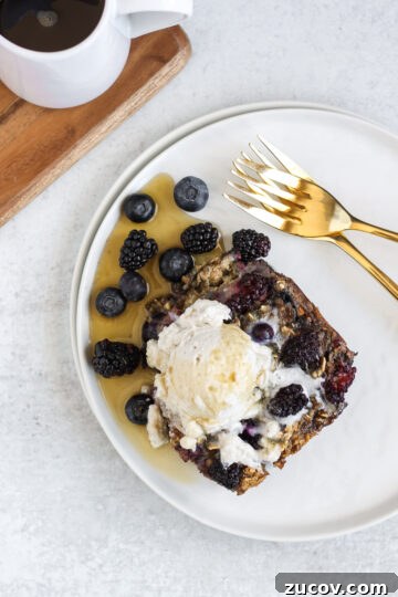 overhead view of a piece of baked berry oatmeal with coconut whipped cream and syrup on top