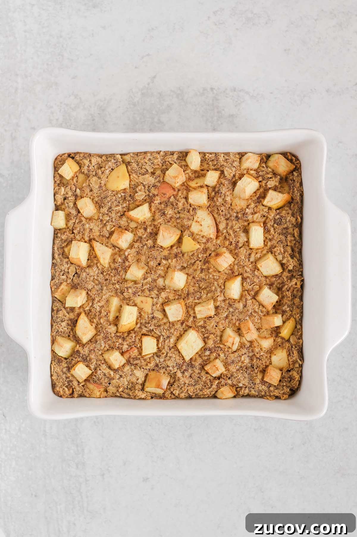 Baked apple cinnamon oatmeal in a square white baking dish.