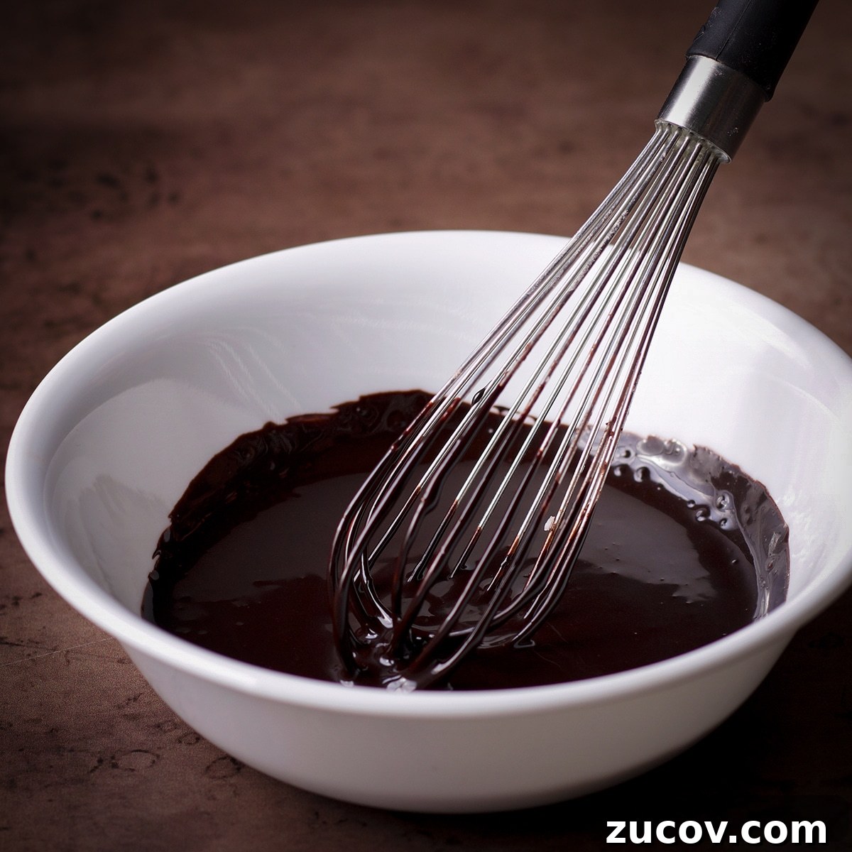 Chocolate Banana Muffins with Oats and Dark Cocoa 11 Someone using a wire whisk to mix up a simple chocolate glaze for double chocolate banana muffins.