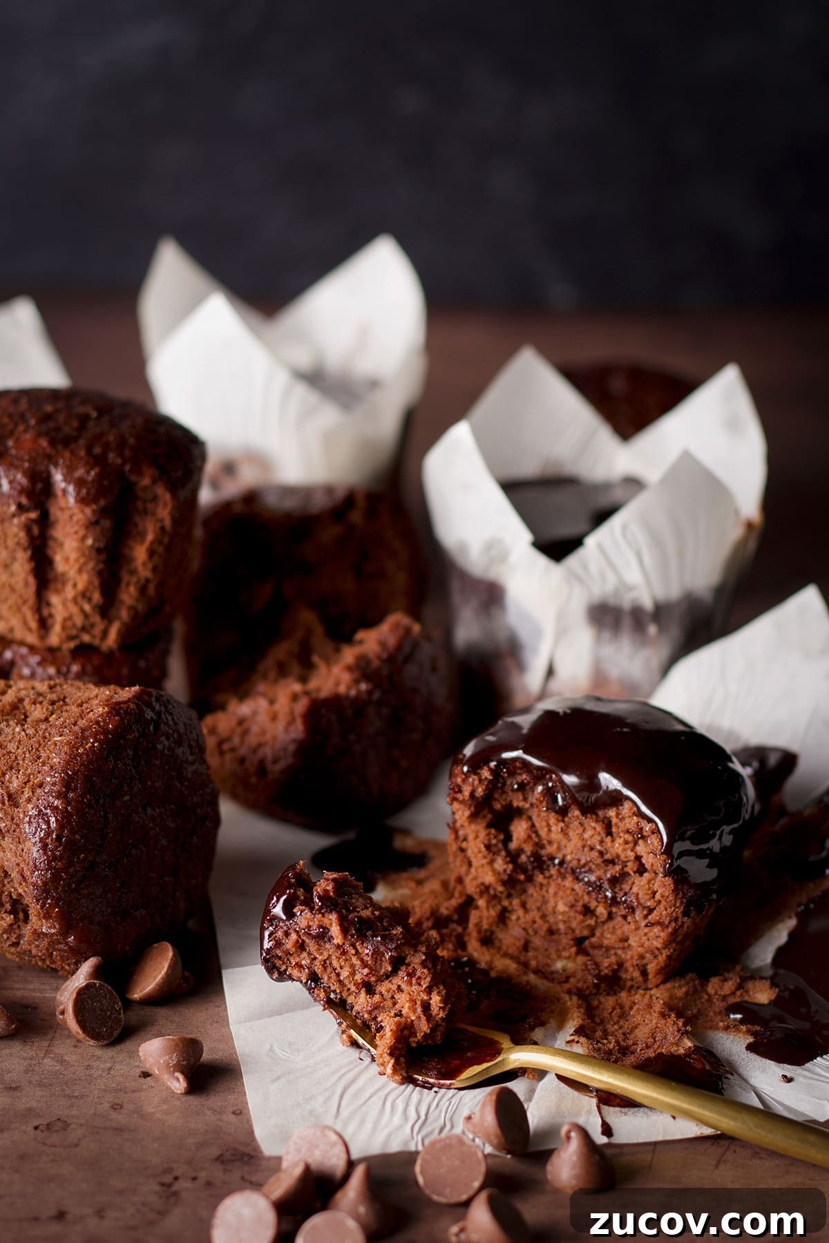 Chocolate Banana Muffins with Oats and Dark Cocoa 17 Healthy chocolate banana muffins on a table with chocolate chips scattered around them.