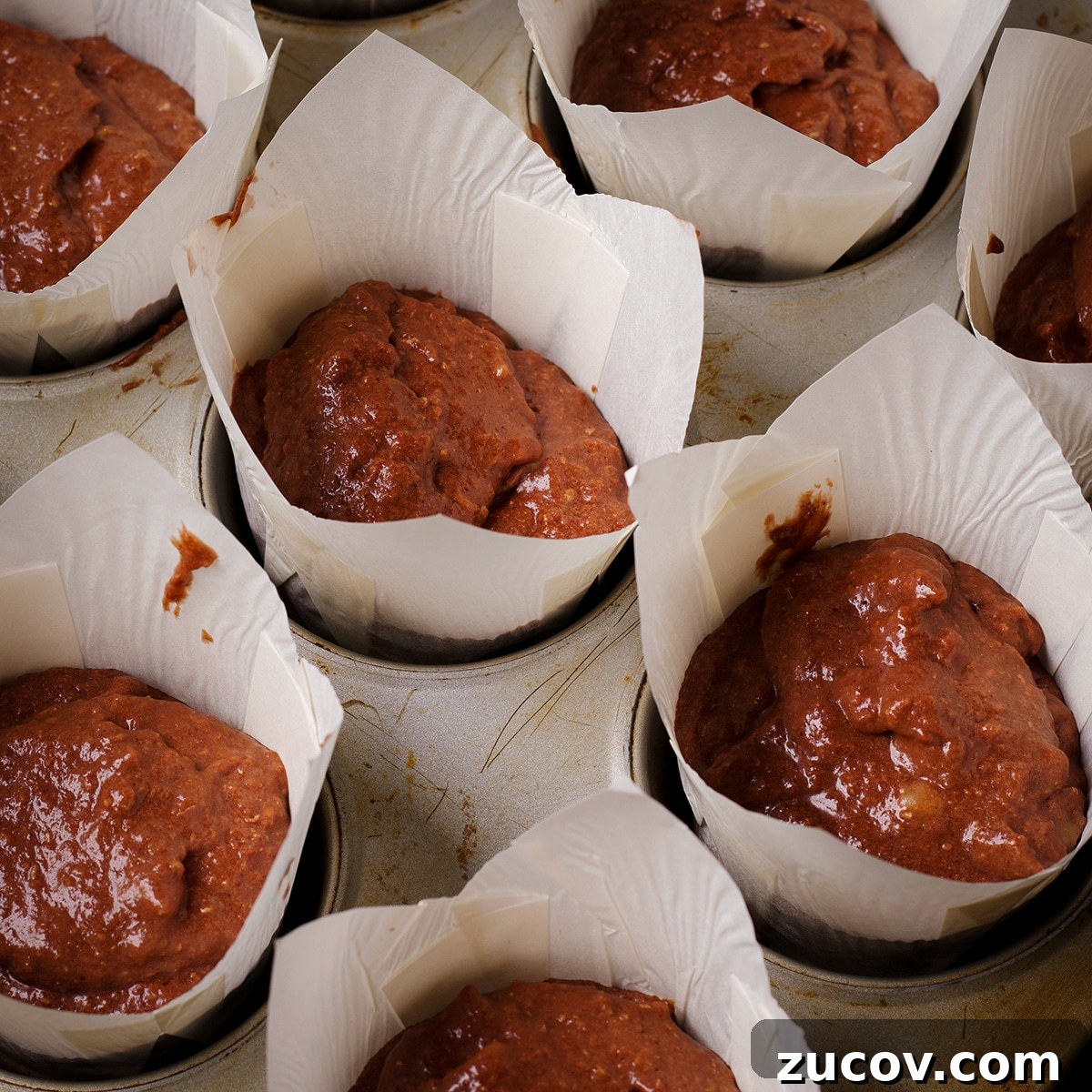 Chocolate Banana Muffins with Oats and Dark Cocoa 10 A muffin tin containing tulip paper liners that have been filled with chocolate banana muffin batter.